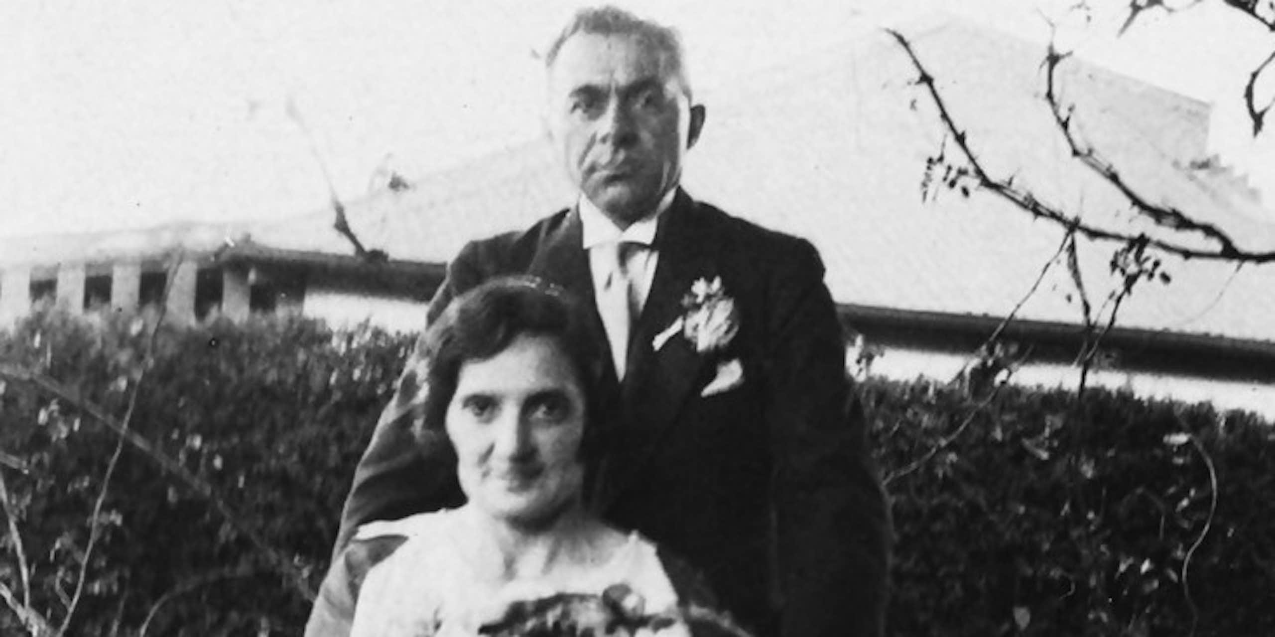 Black and white photo of a seated woman holding a bouquet of flowers and a man standing behind her