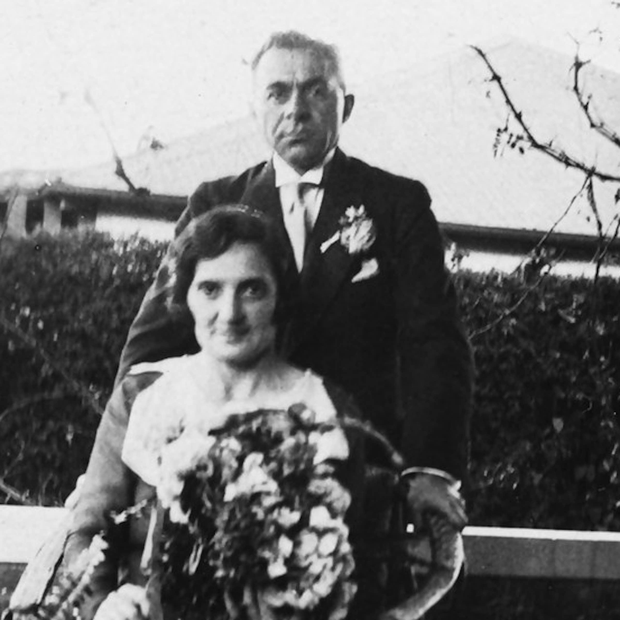Black and white photo of a seated woman holding a bouquet of flowers and a man standing behind her