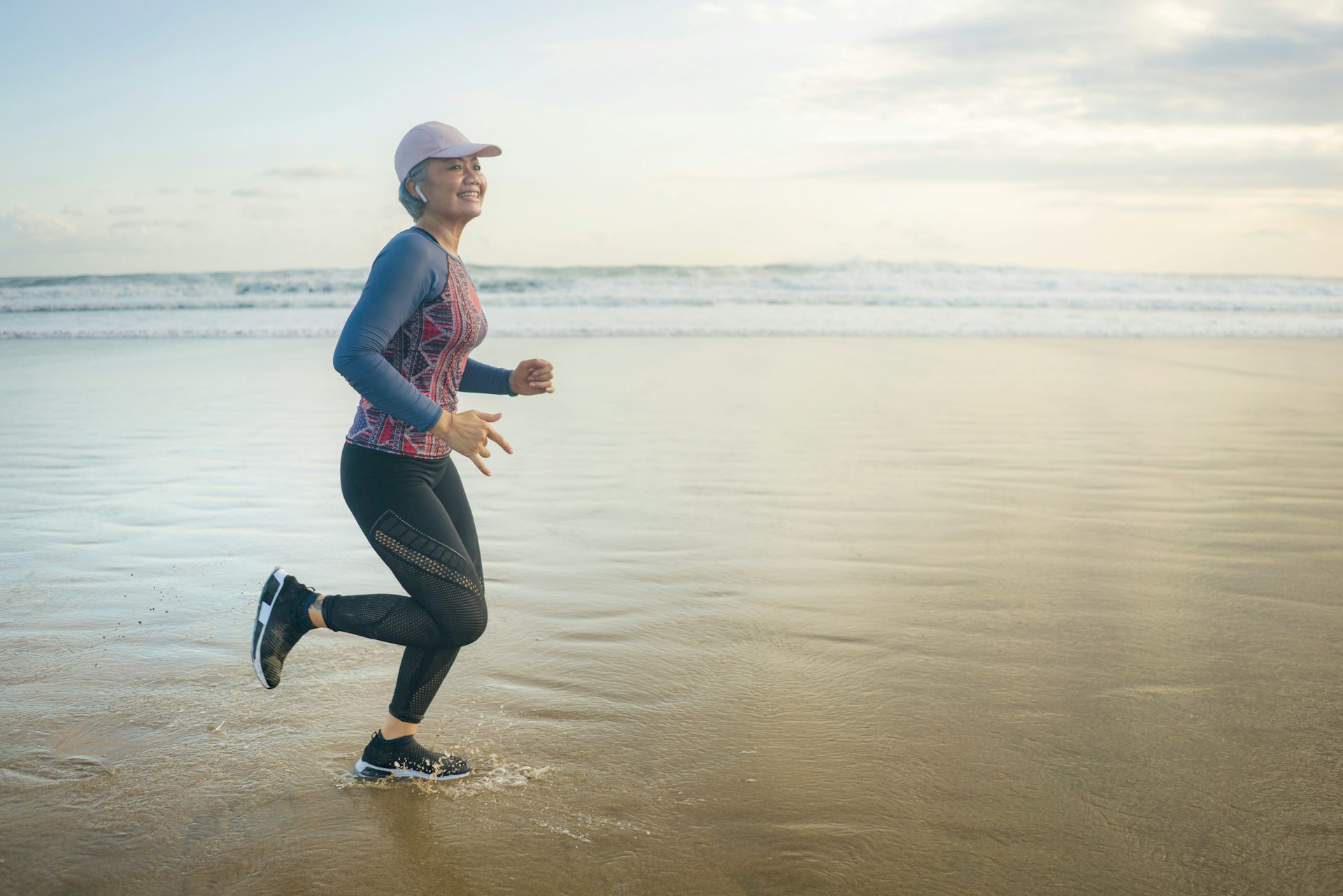 A middle-aged woman runs on a beach.