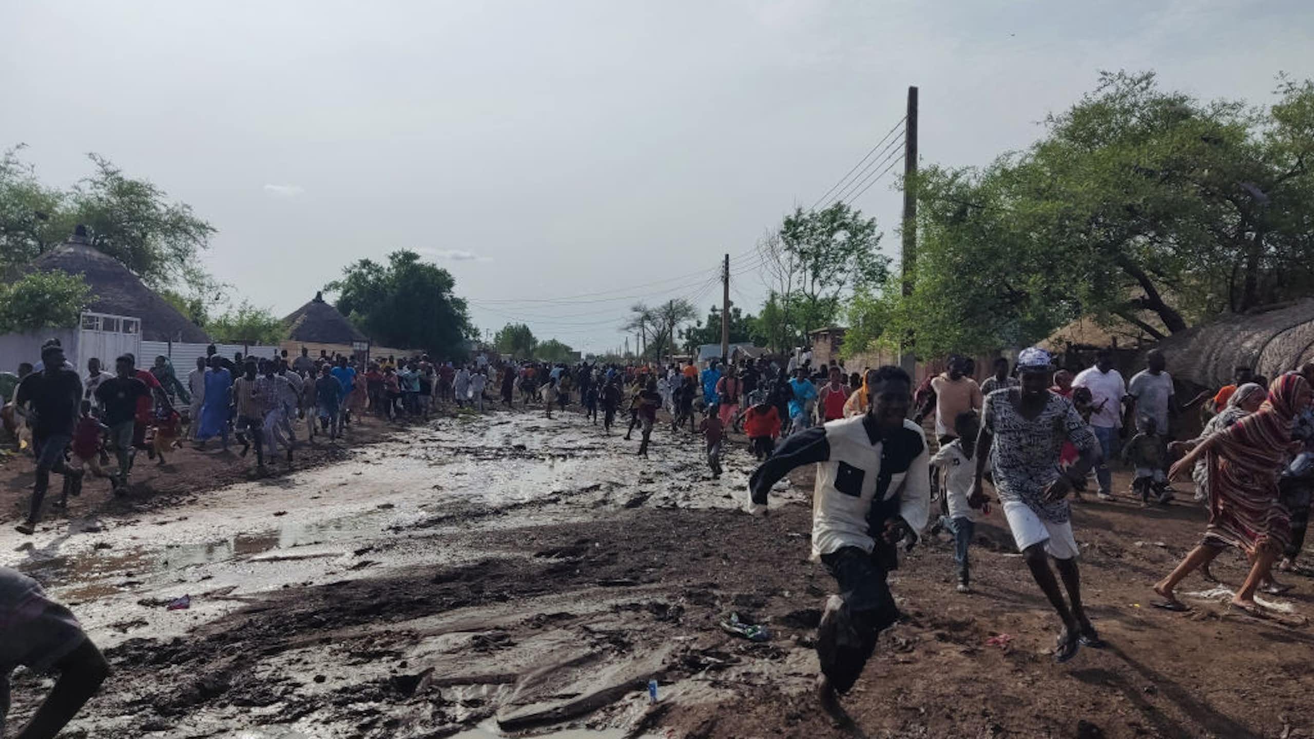 A group of people running on muddy ground
