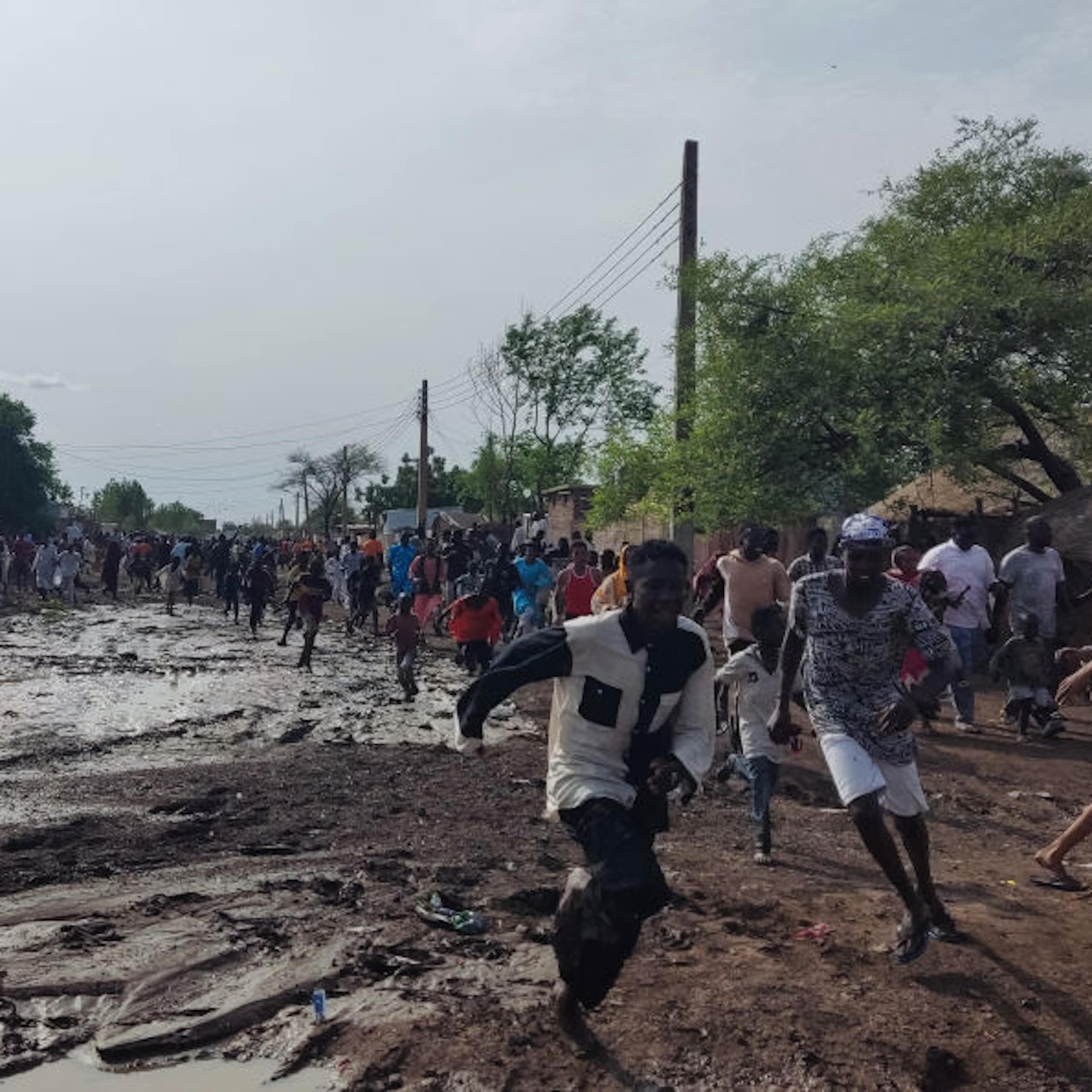 A group of people running on muddy ground