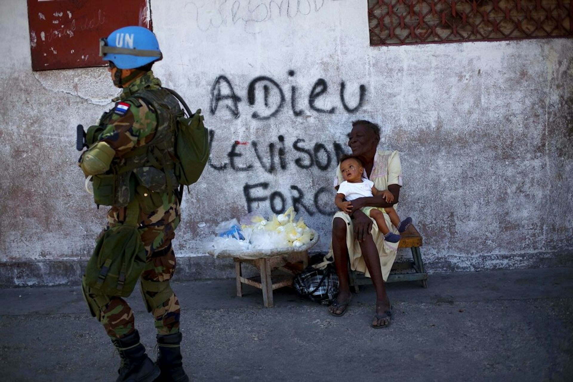 A soldier walks down a street past civilians.