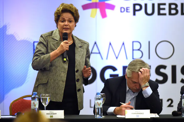 Former Brazilian president Dilma Roussef, stands speaking into a microphone.