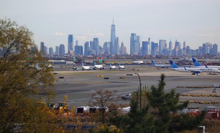 Grounded airplanes are seen in front of a city landscape.