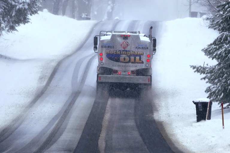 A fuel truck on an icy road with snow all around.