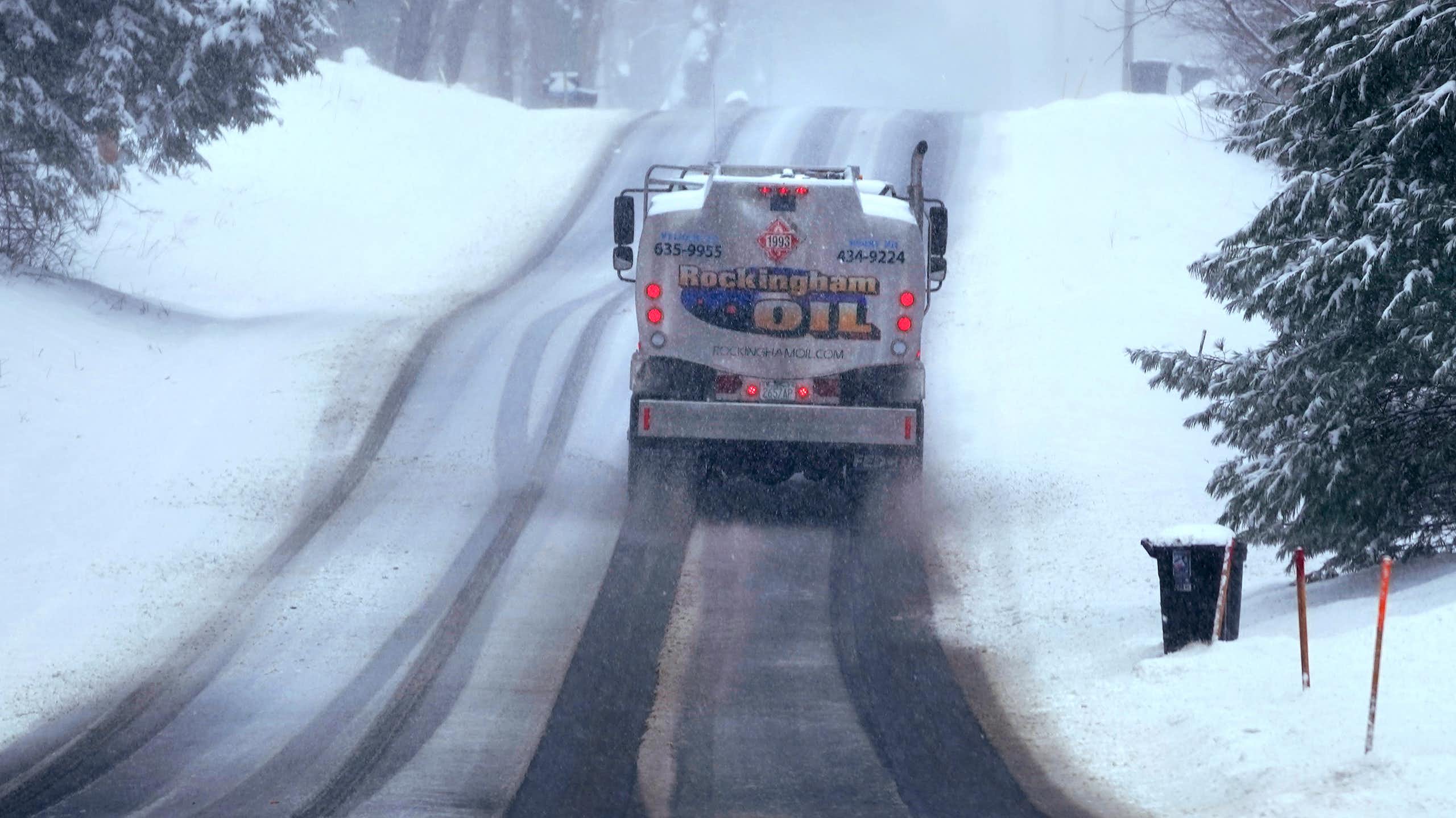 A fuel truck on an icy road with snow all around.