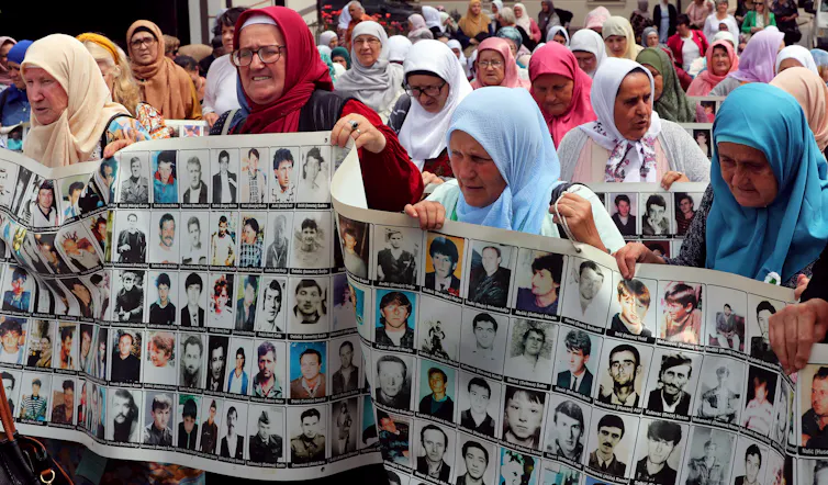 Grieving women hold pictures of their dead relatives.