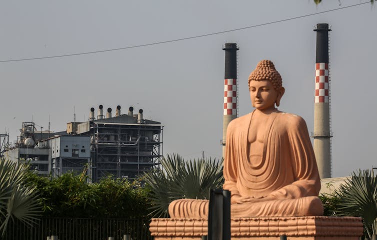 Buddha statue in front of coal power plant