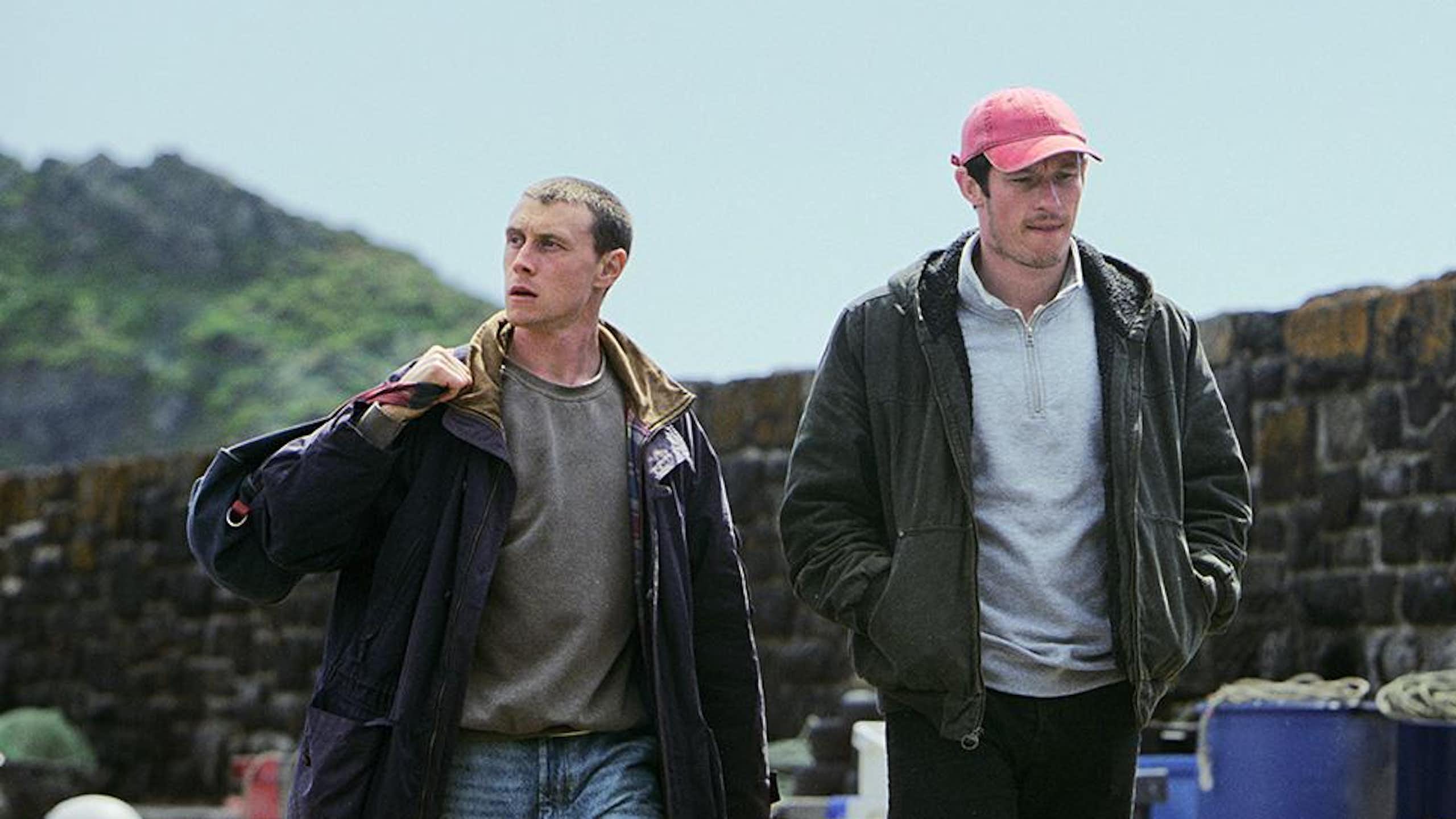 George MacKay and Callum Turner walking in a fishing village