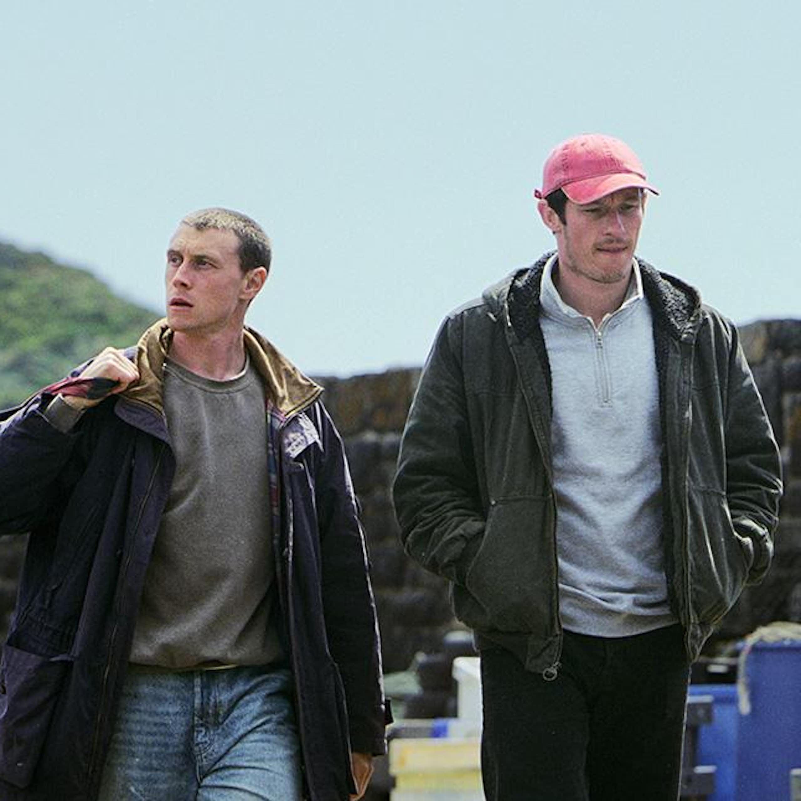 George MacKay and Callum Turner walking in a fishing village