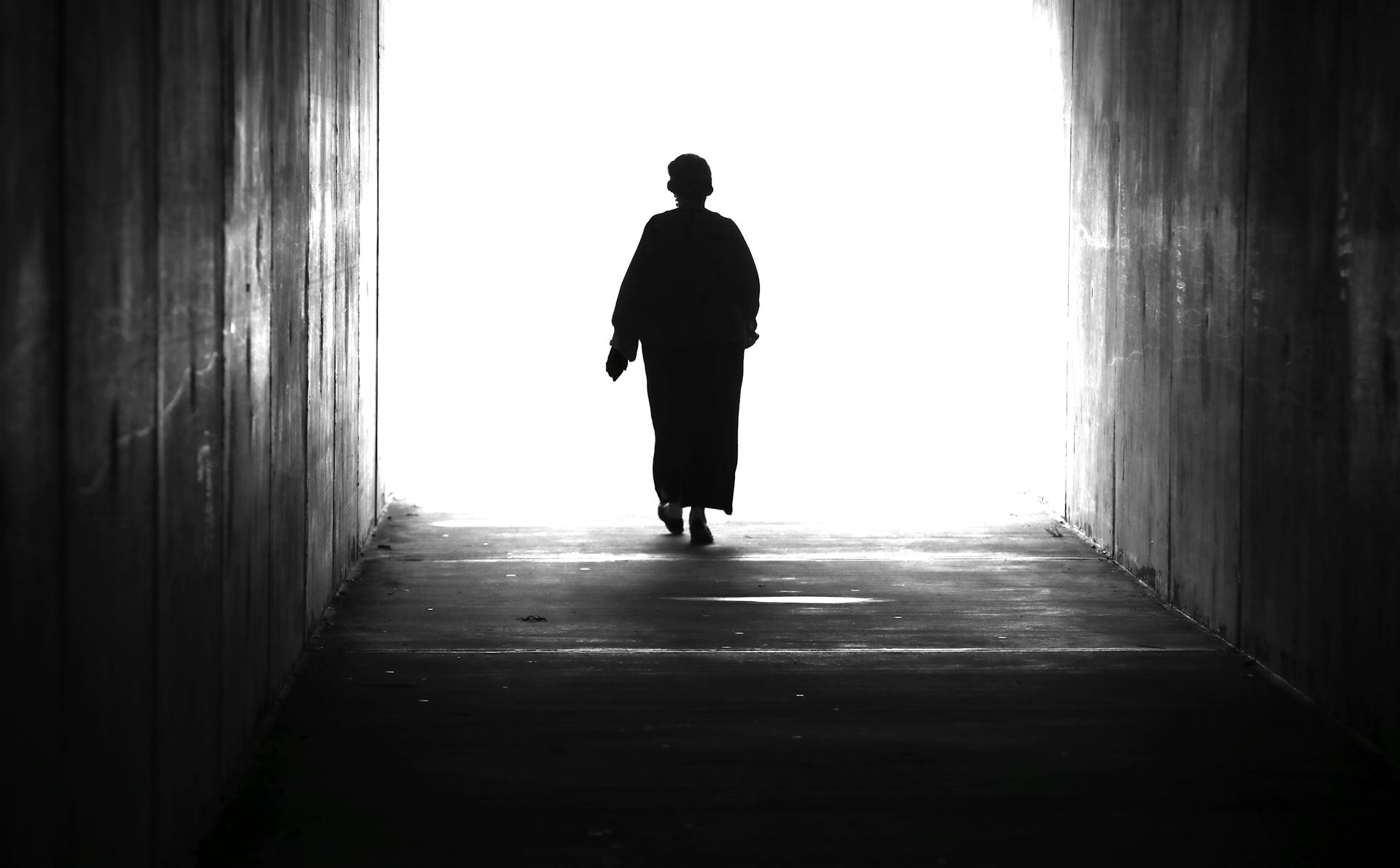 A woman walking towards a bright light.