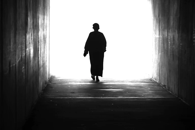 A woman walking towards a bright light.