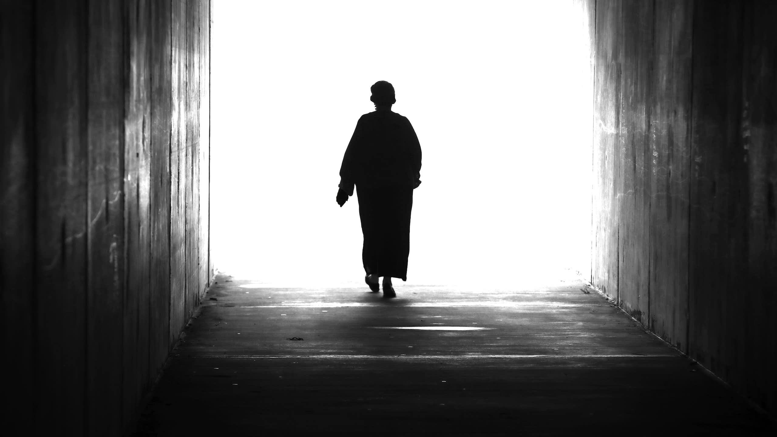 A woman walking towards a bright light.