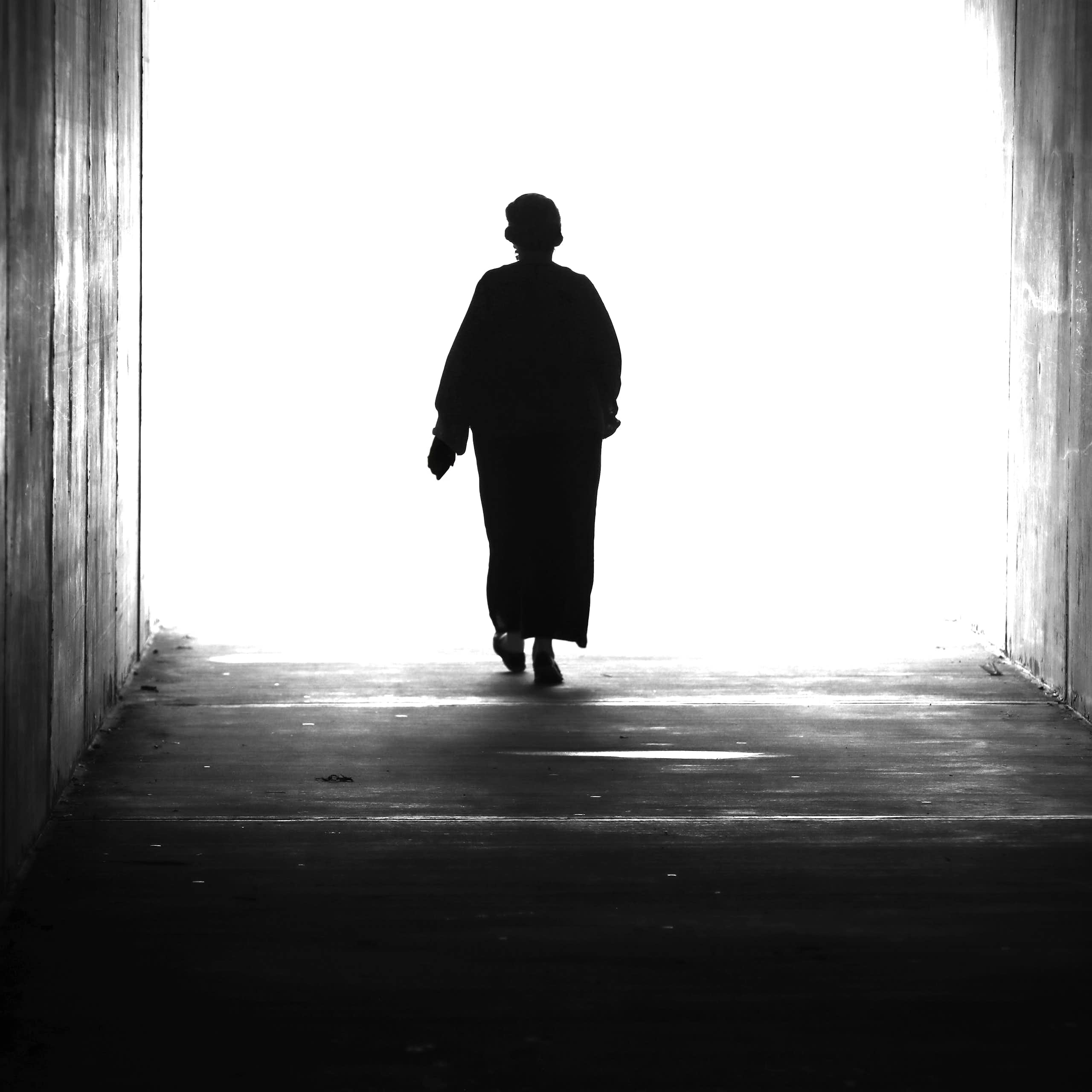 A woman walking towards a bright light.