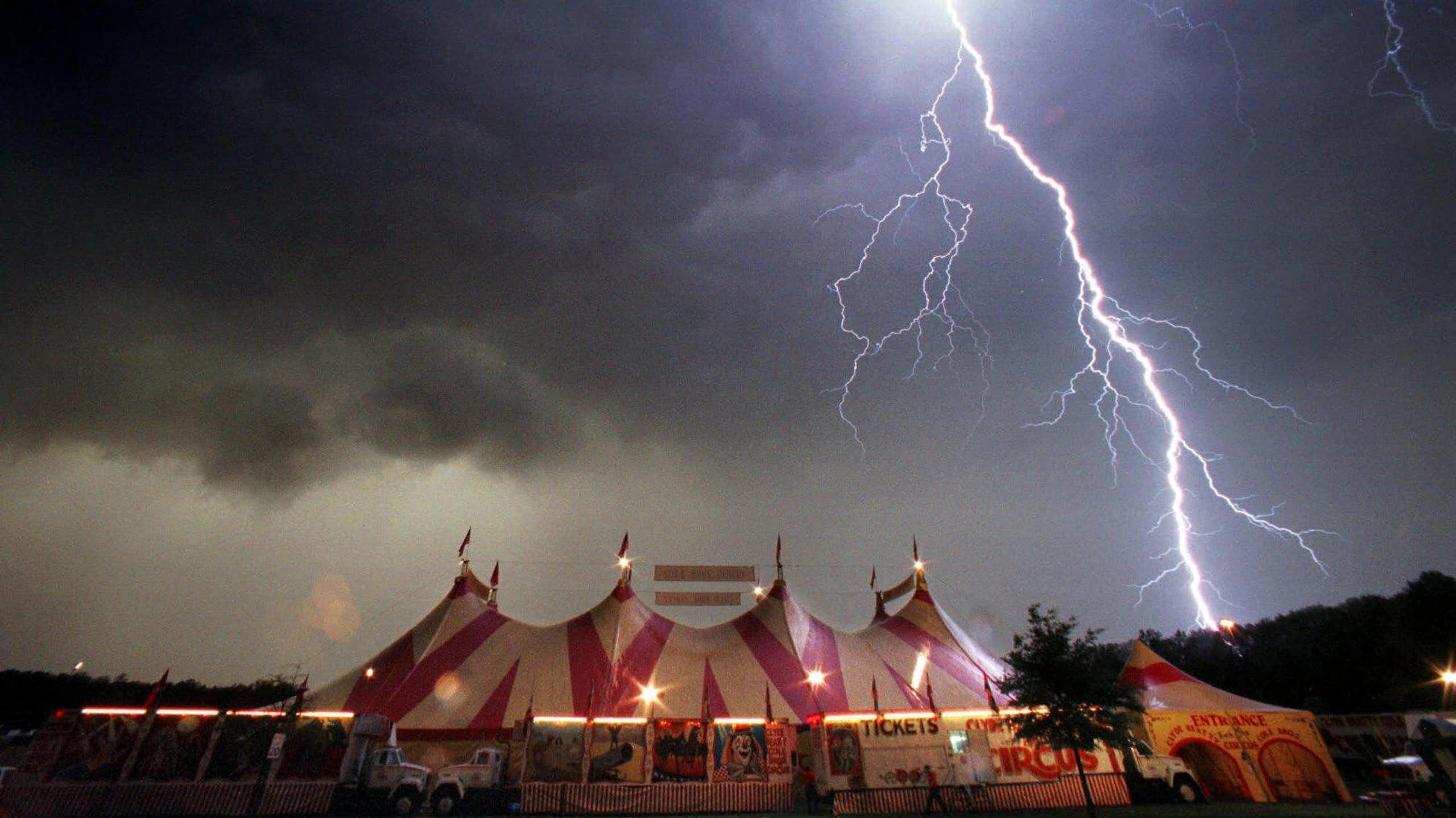 A dark sky and lightning seen over a circus tent.