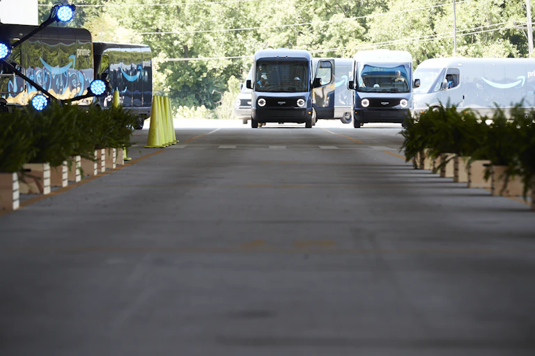 Electric delivery vans with drivers getting into them.
