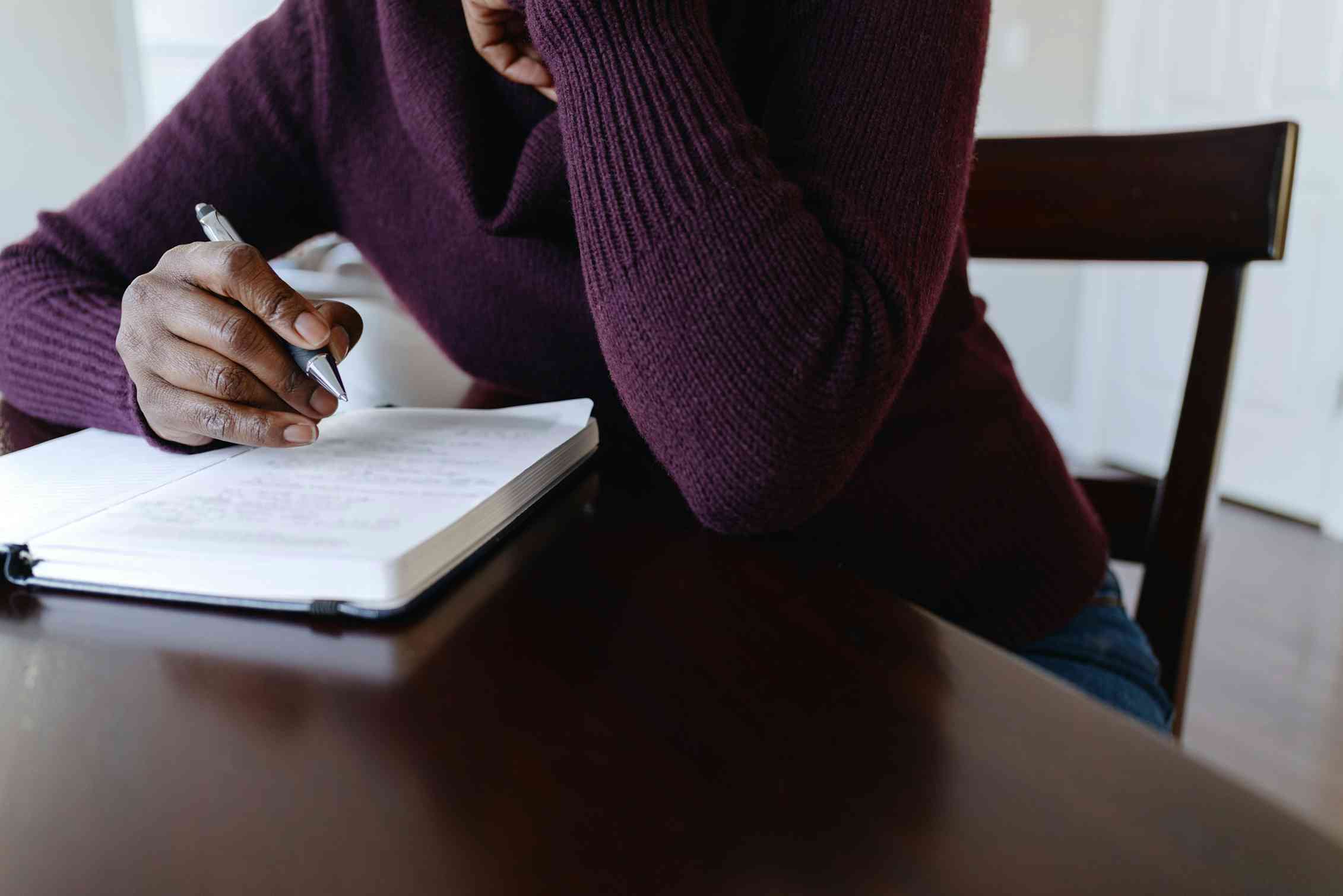 Person sitting at a table writing in a notebook
