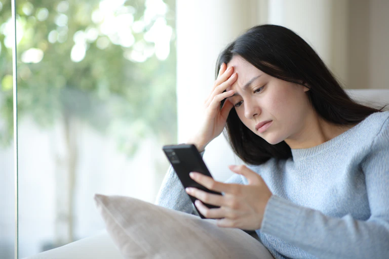 woman looking at her phone with a furrowed brow