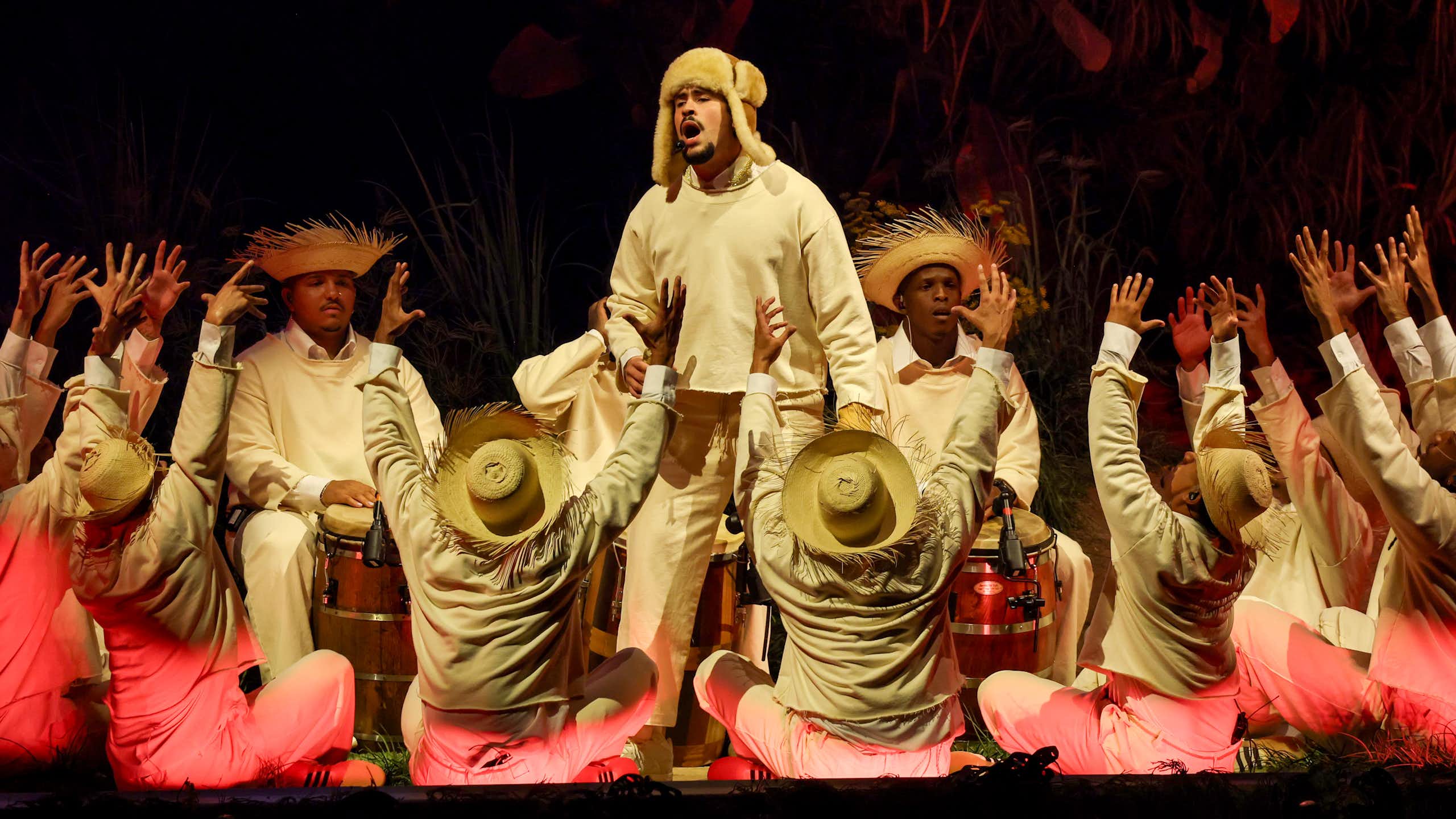 A man signs on a stage as dozens of others surround him.