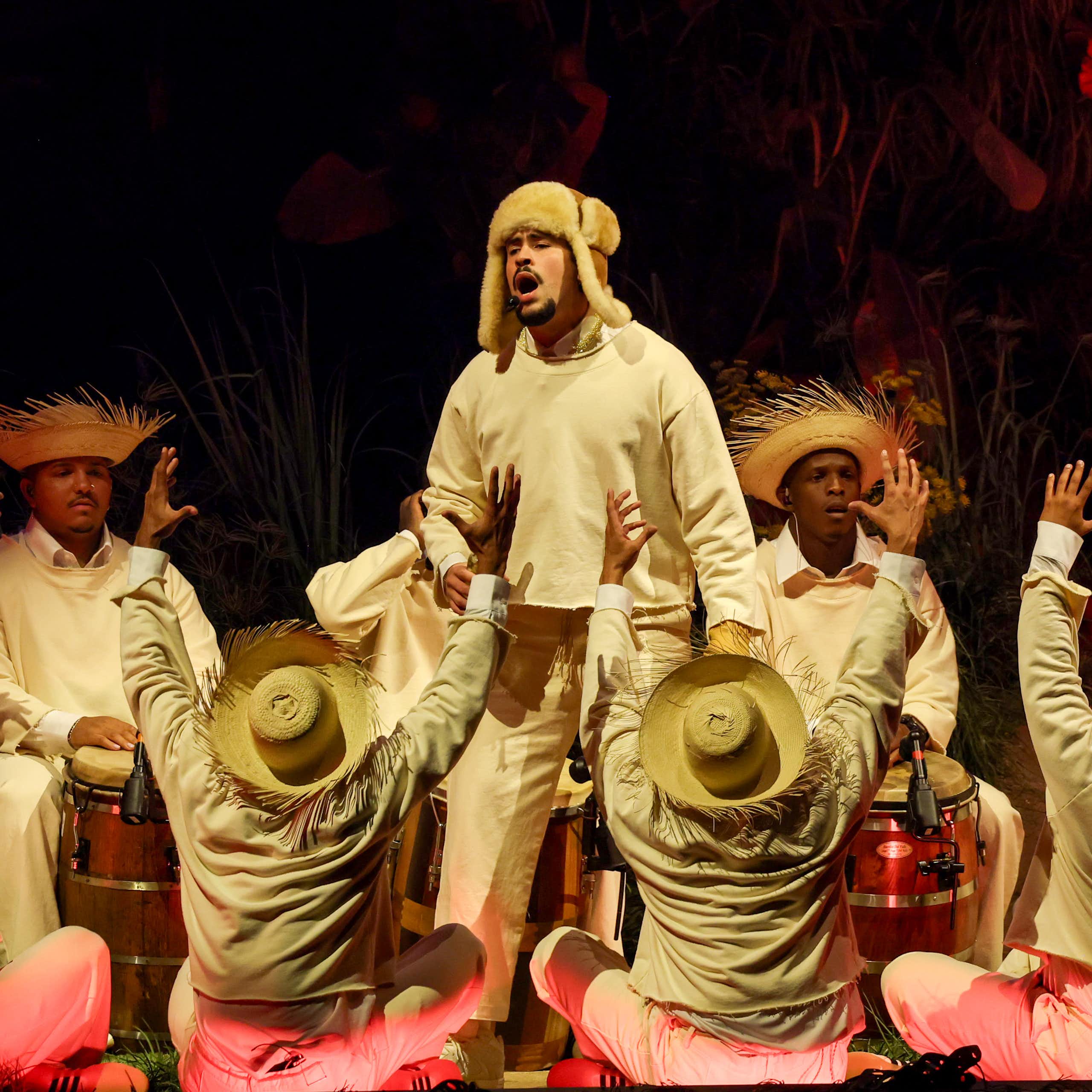 A man signs on a stage as dozens of others surround him.