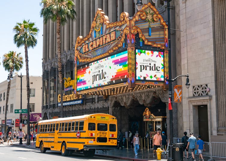 A theater billboard promotes LGBTQIA+ rights and a movie.