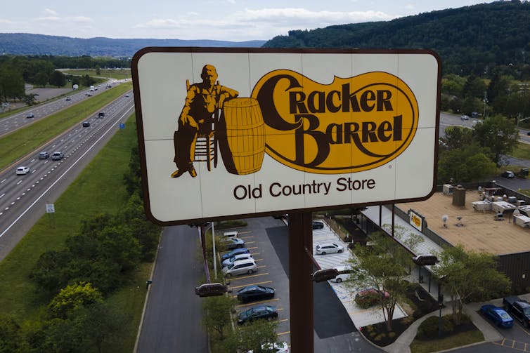 A sign promoting a restaurant appears next to a highway.