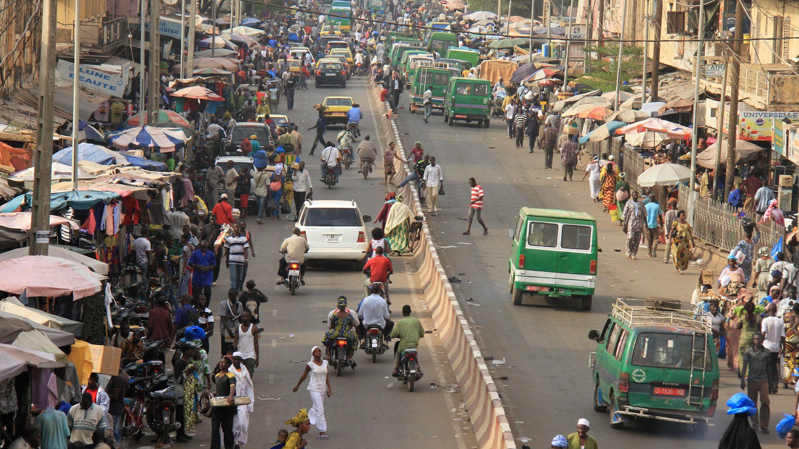 People and cars move along a busy roadway