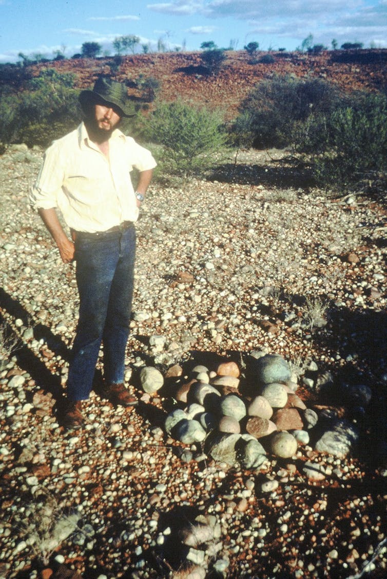 A man stands next to rocks.