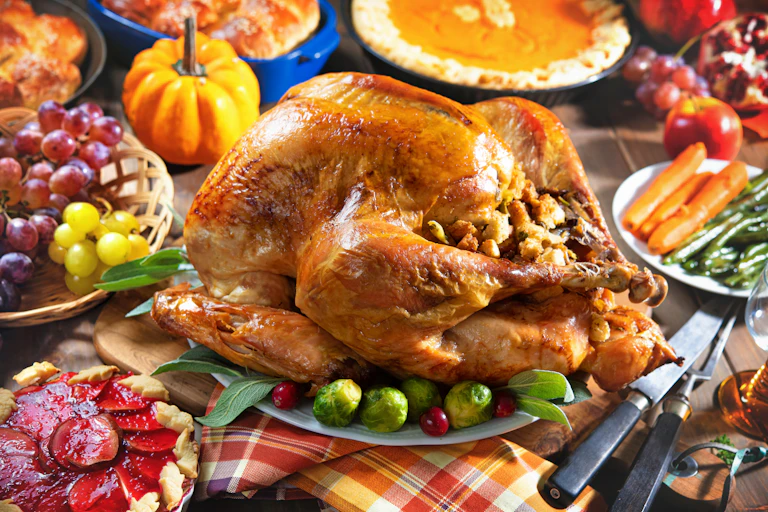 A Thanksgiving feast, including a roast turkey with stuffing, pies and roasted vegetables.