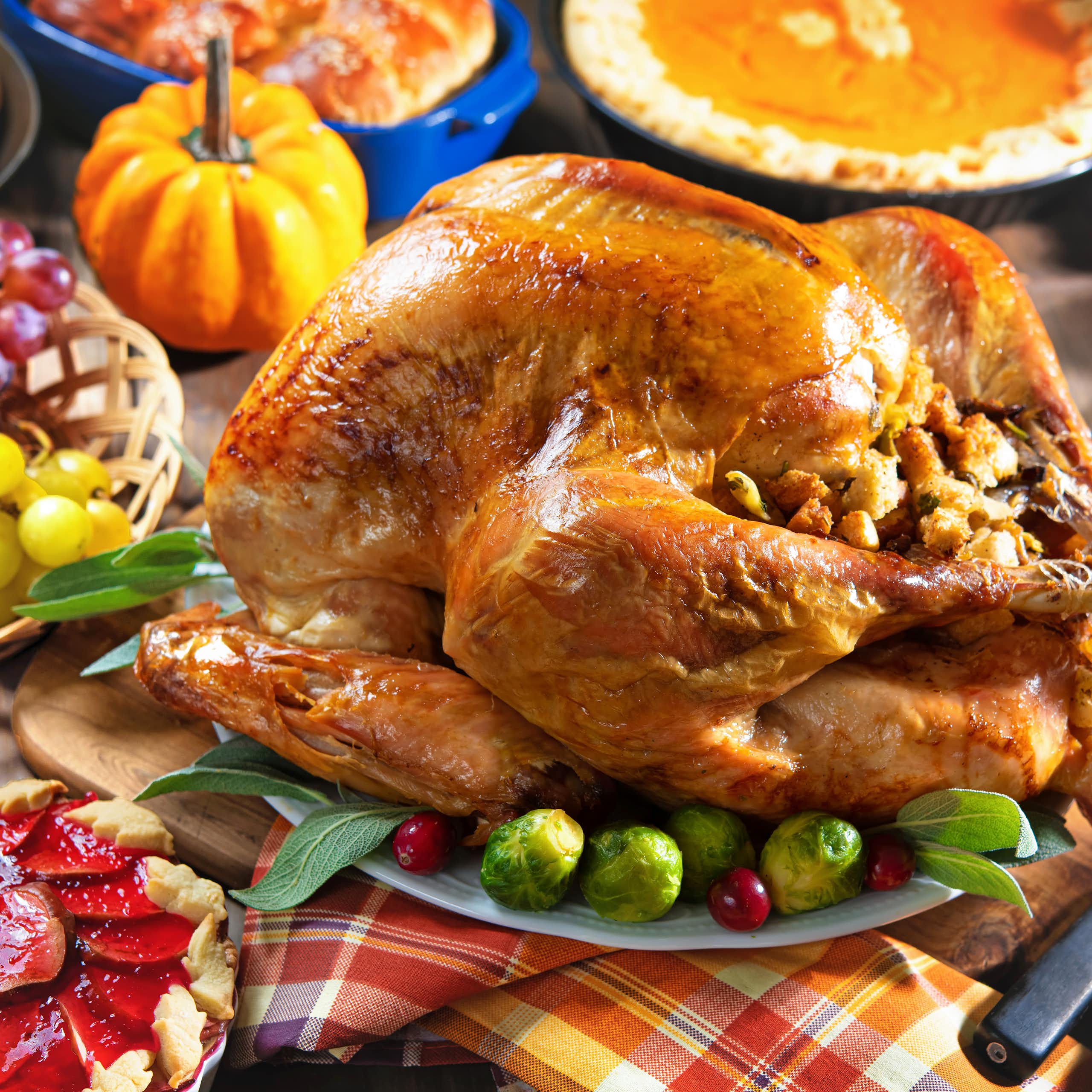 A Thanksgiving feast, including a roast turkey with stuffing, pies and roasted vegetables.