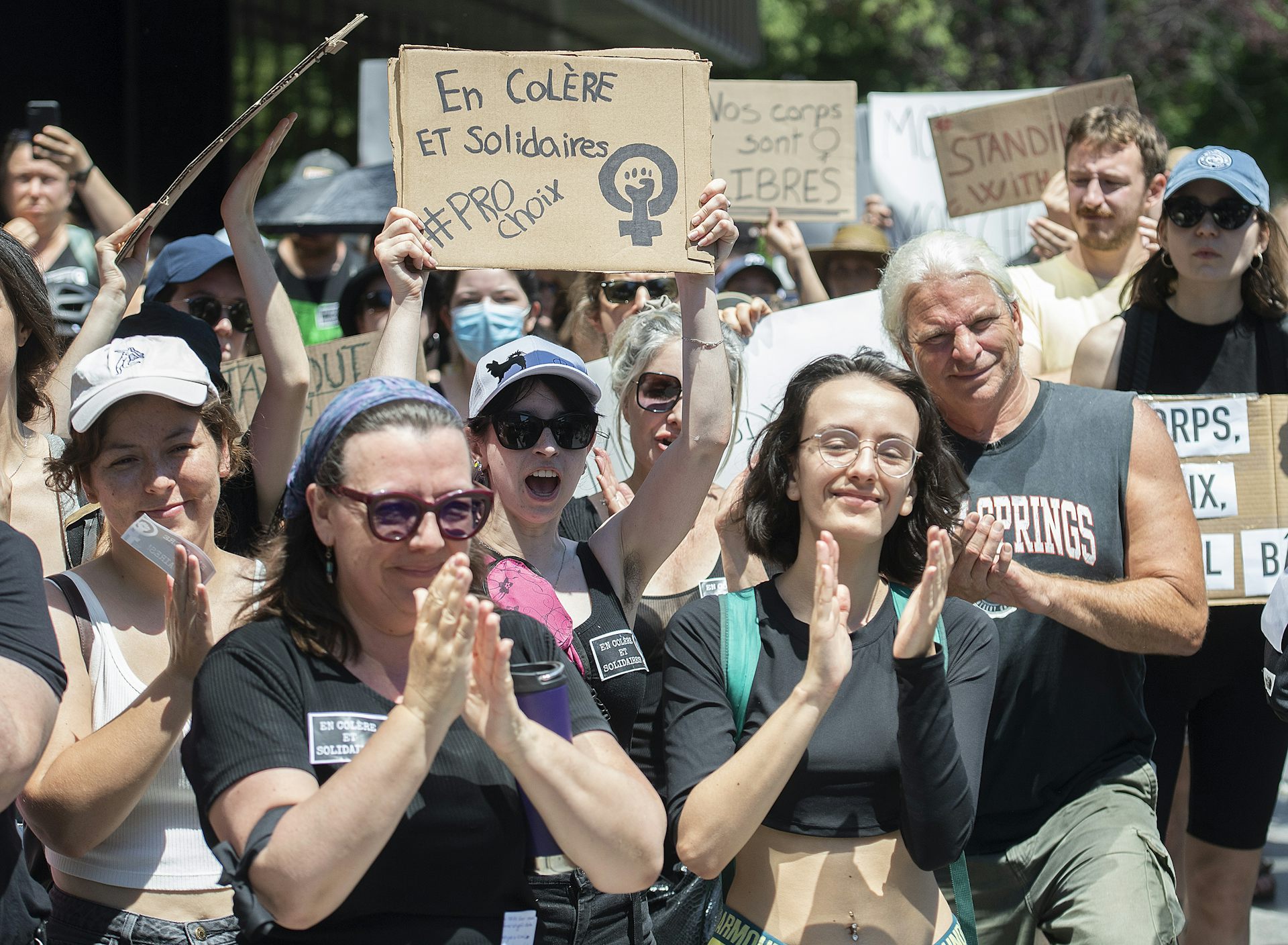 Des personnes participent à une manifestation à Montréal et brandissent des pancartes