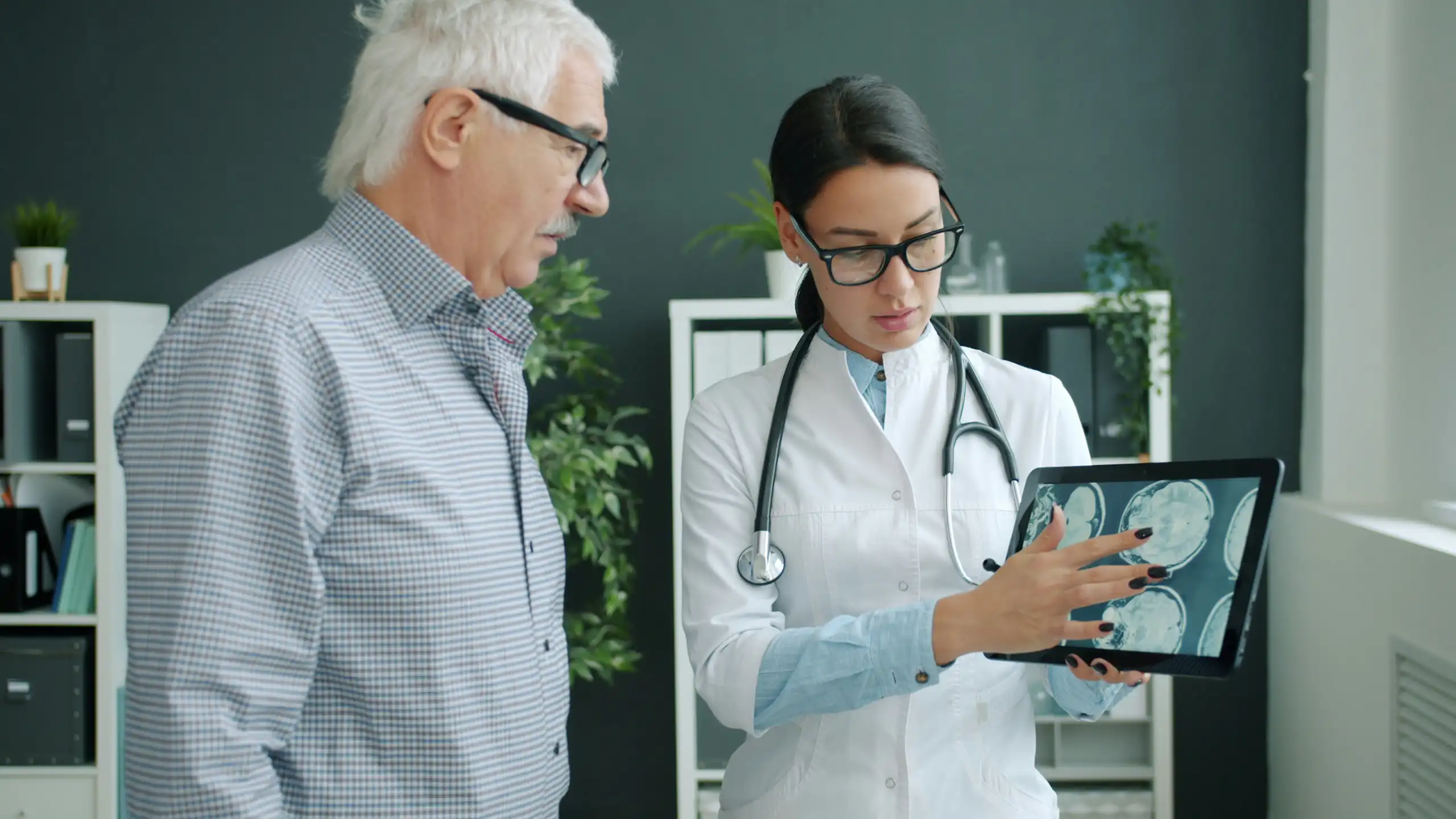 Une médecin montre des images de cerveaux à un homme âgé