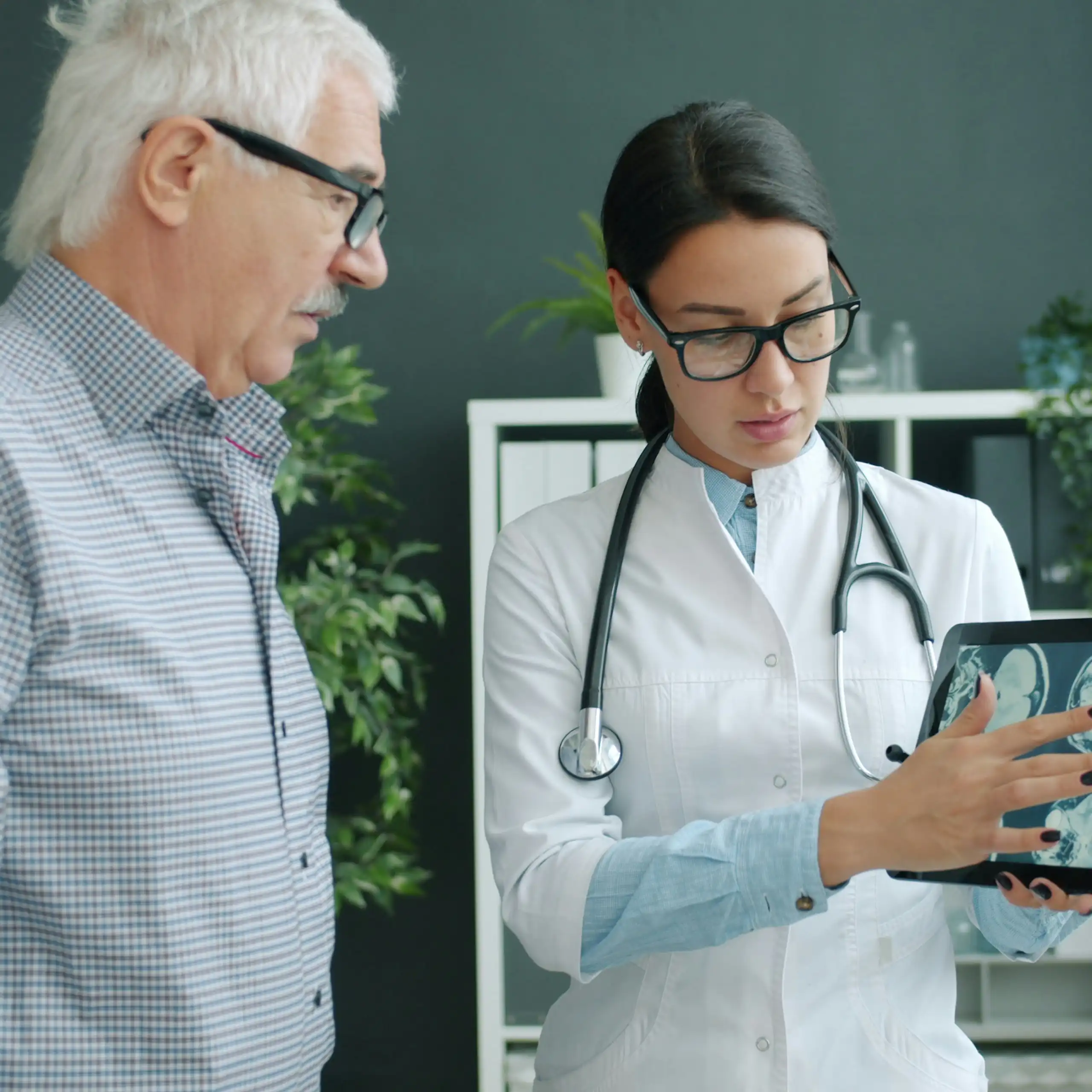 Une médecin montre des images de cerveaux à un homme âgé