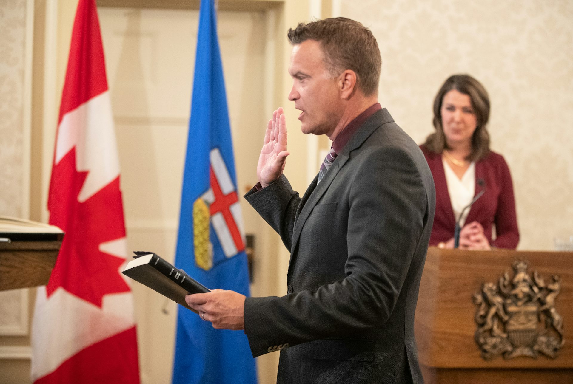 A man takes an oath as a dark-haired woman looks on.