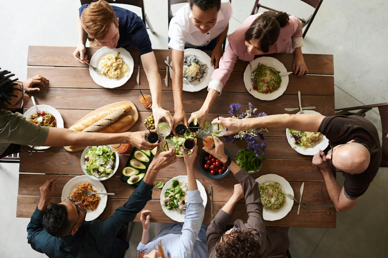 Overhead view of friends or family sitting at table, toasting glasses, unch or dinner on table