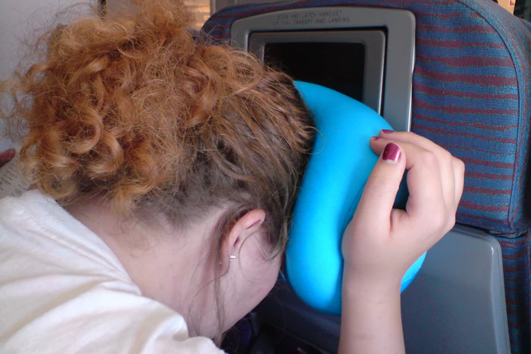The back of a red-headed woman's head as she leans forward in the brace position on a plane.