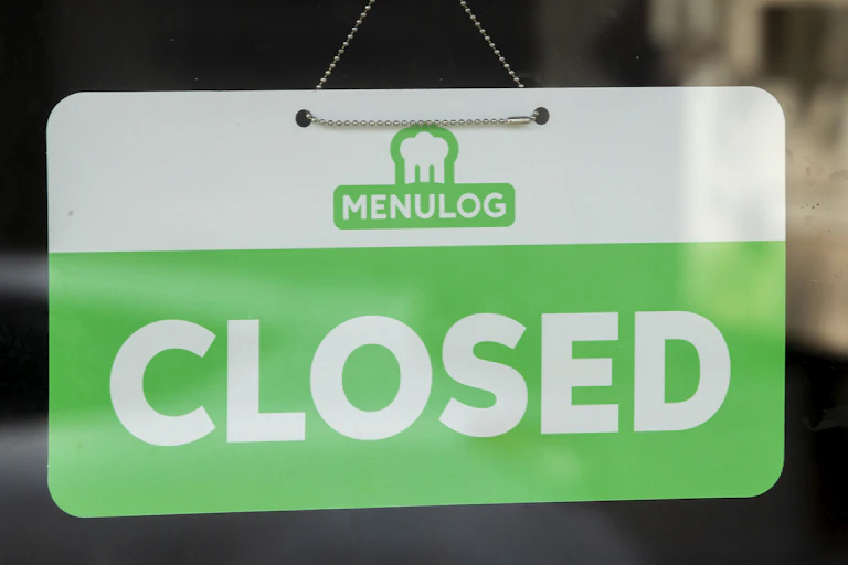 A menulog branded closed sign is seen in a shop window