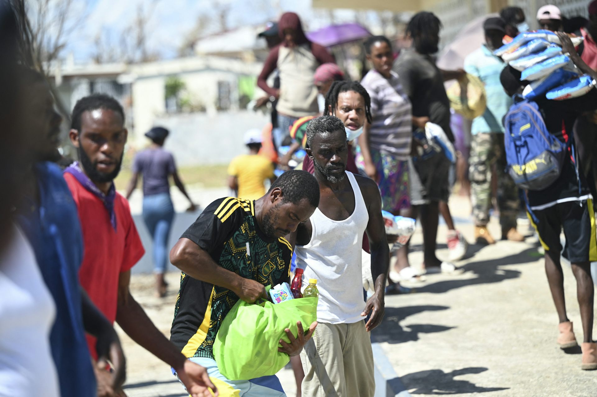 A line of people pass bags of food items one to another.