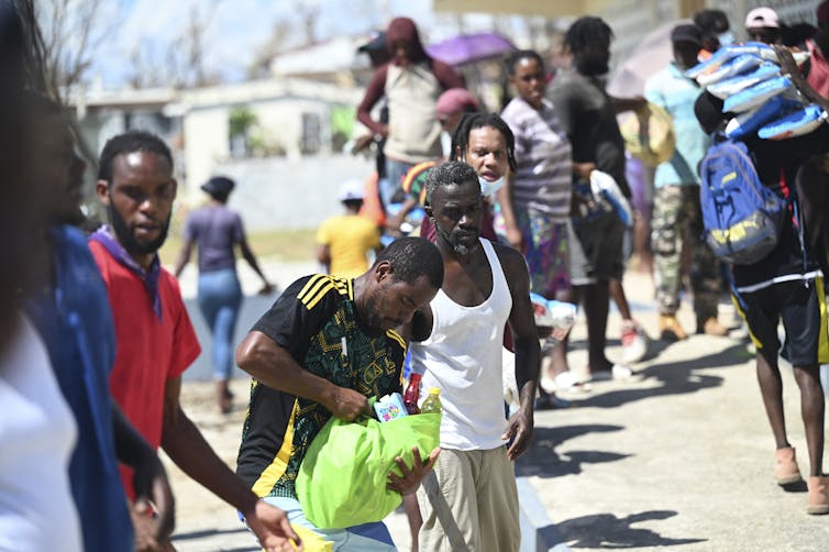 No time to get well: Typhoon Melissa and the Caribbean’s compounding crisis lure 2 A line of people pass bags of food items one to another.