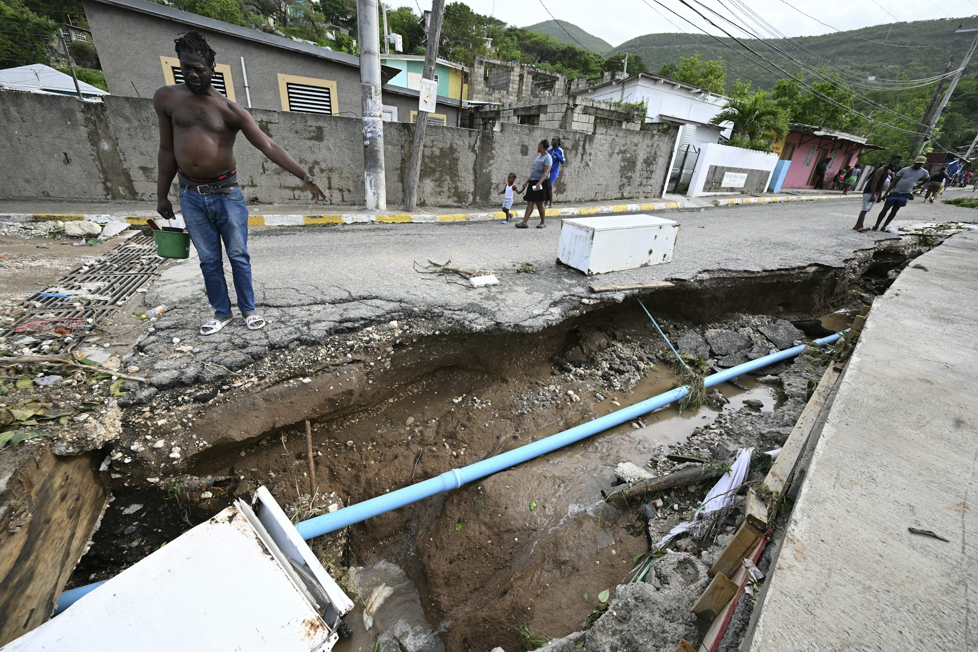 A man looks into an open drainage area that has been torn up out by the storm
