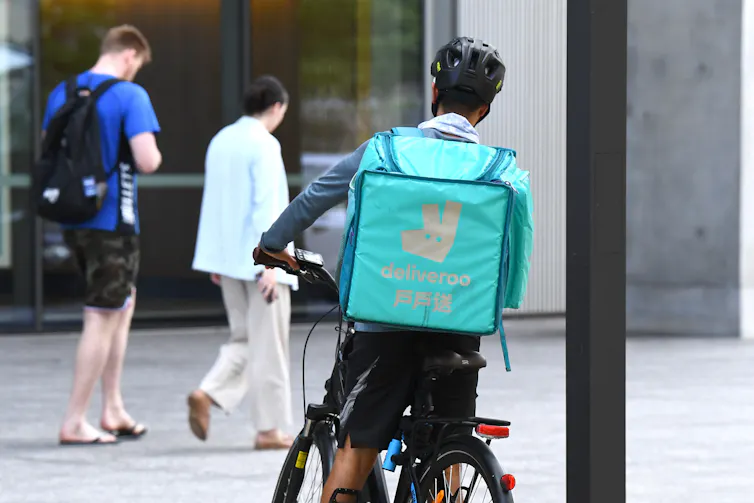 A food delivery rider on a bike with a Deliveroo bag