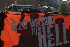Protesters dressed in all black hold up a banner as they take part in the 'Welcome to Hell' protest march on July 6, 2017 in Hamburg, Germany