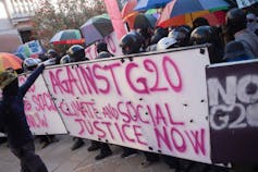 Protestors and a sign that says 'Against G20. Climate and Social Justice now'