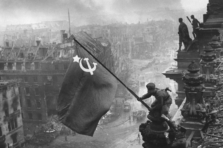 Two Soviet soldiers planting a Soviet flag atop the Reichstag building