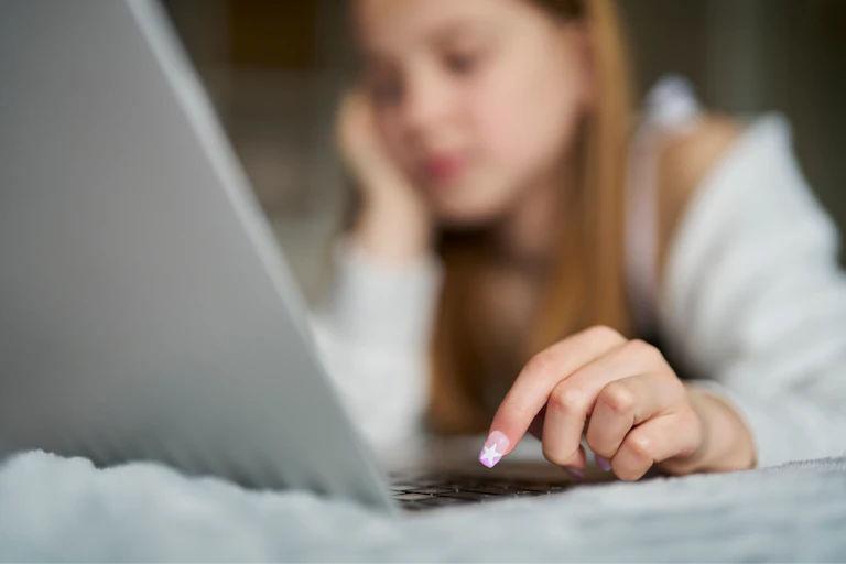 Une jeune adolescente devant un écran d'ordinateur.