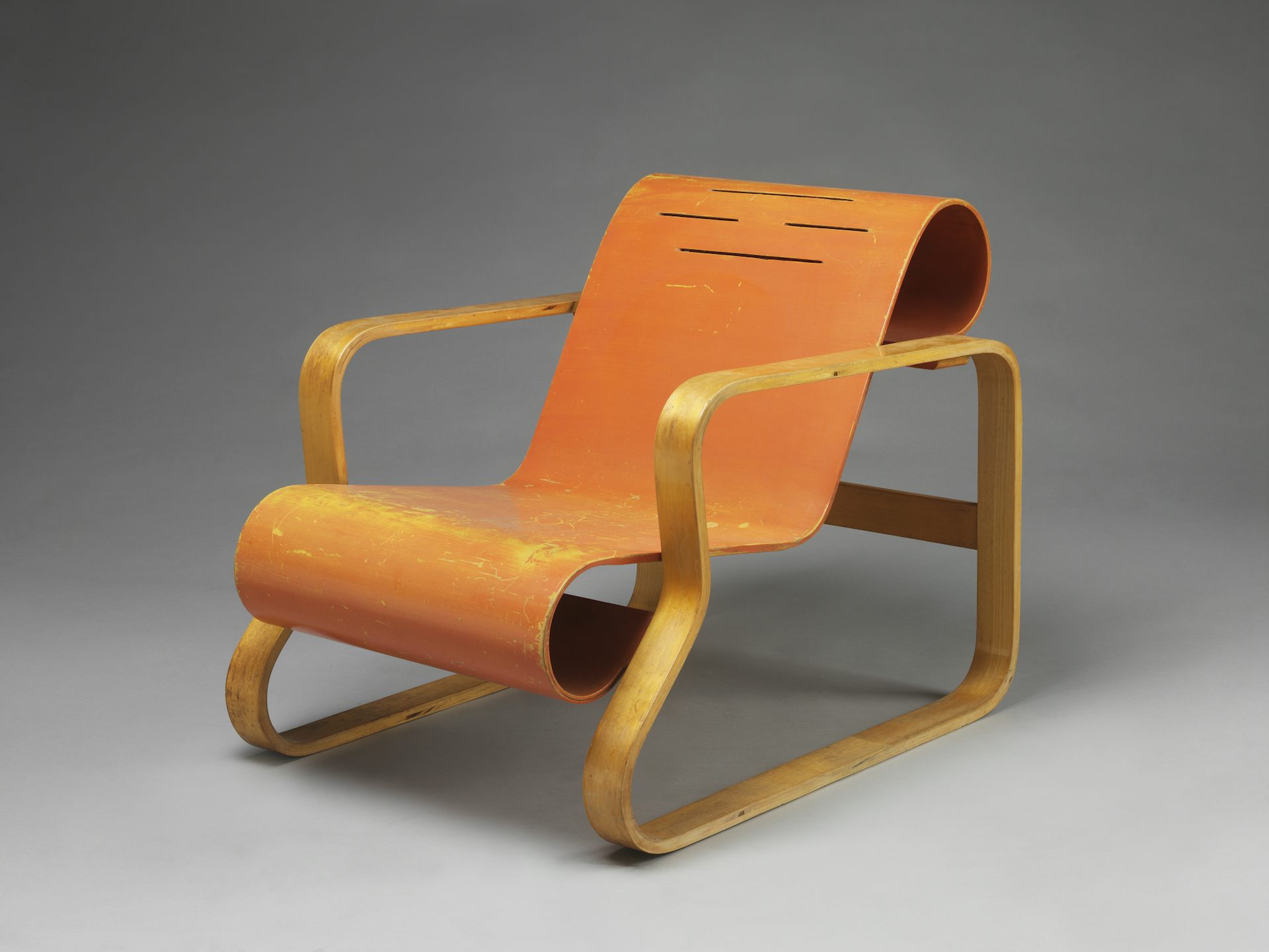 An orange plywood lounging chair.