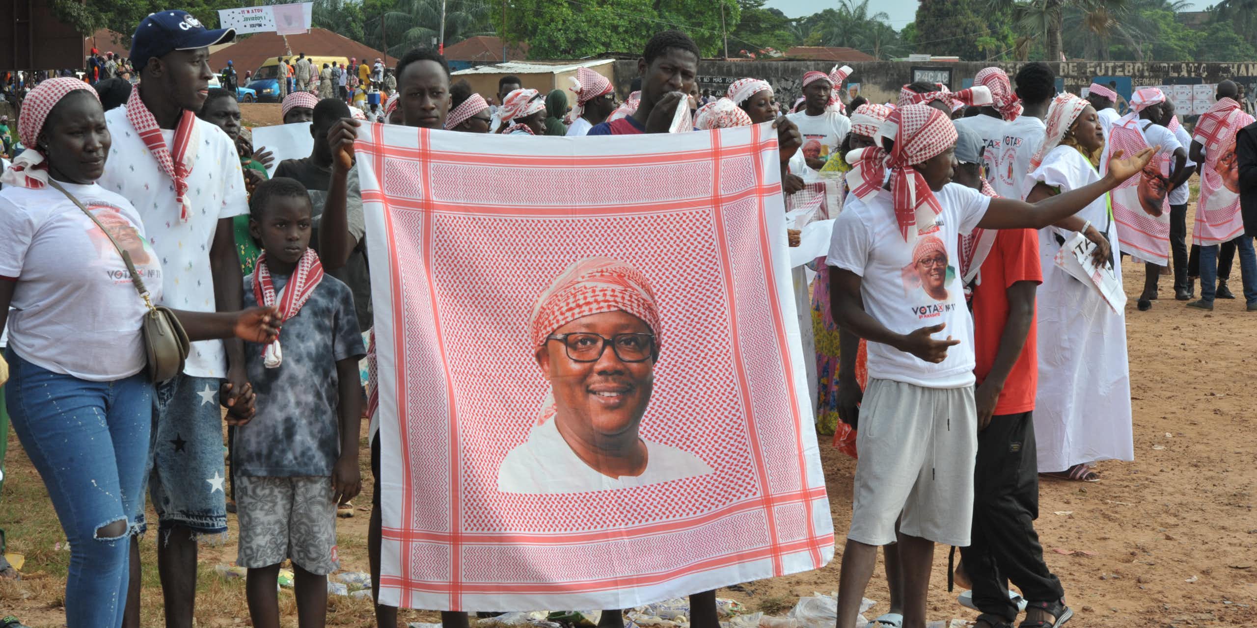 People holding a portrait picture of a man while dancing on the street