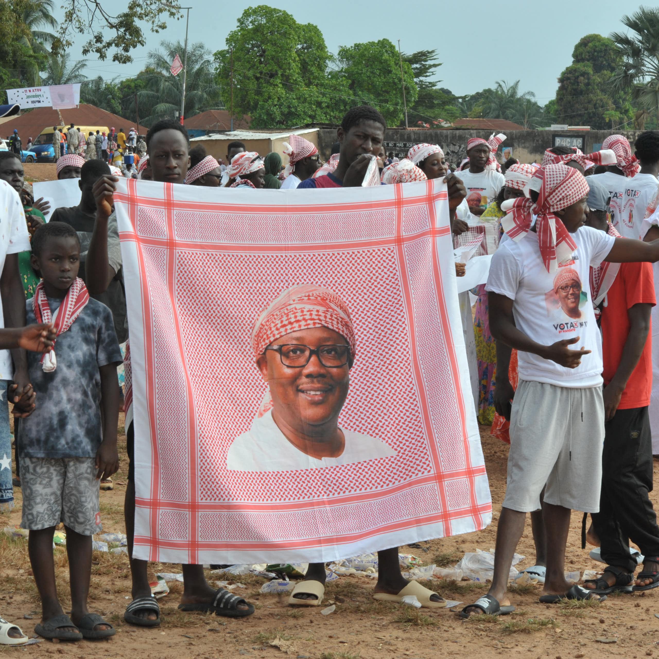 People holding a portrait picture of a man while dancing on the street