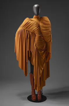 A rusty orange designer dress ruched in style with ornate fringing.