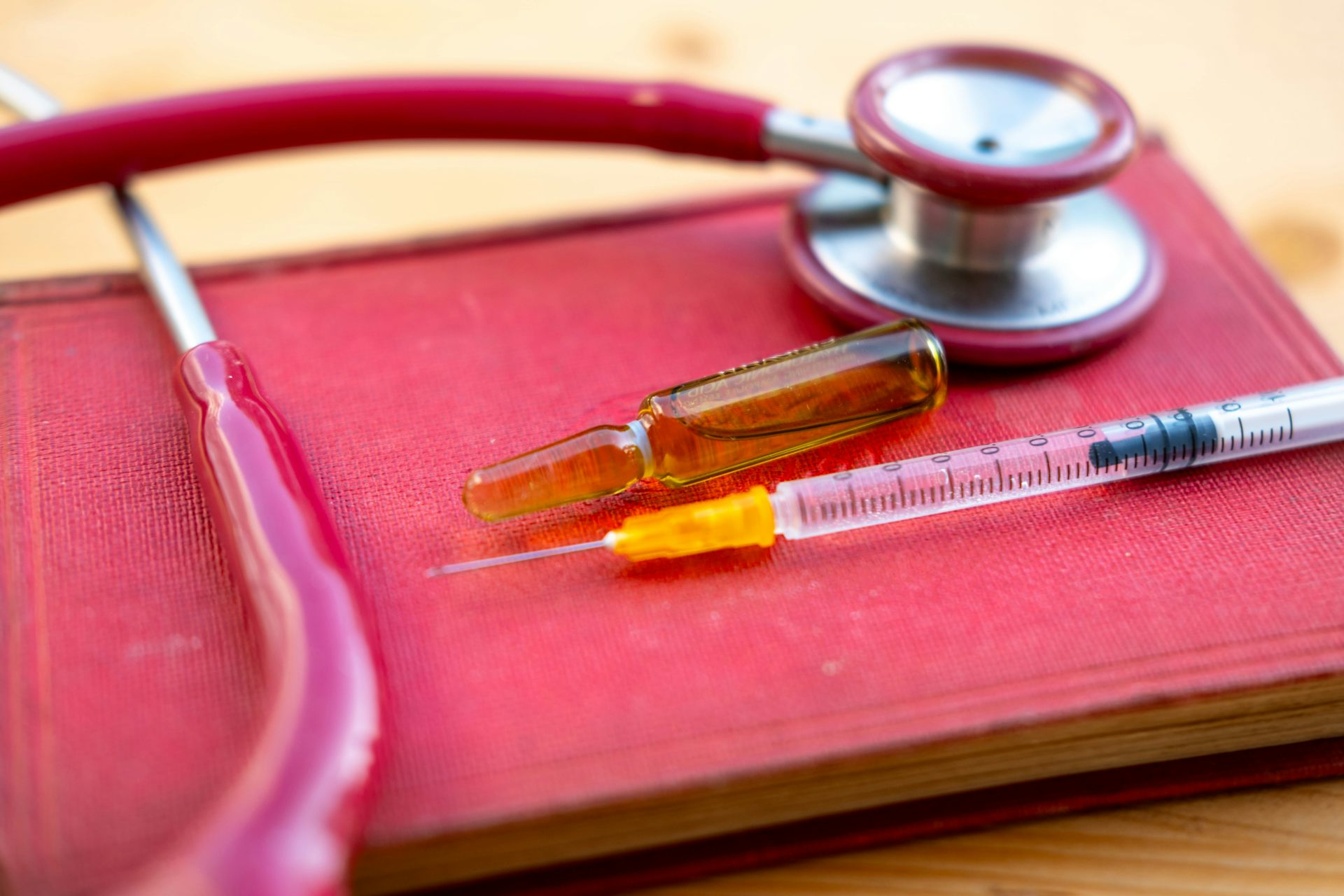 Une seringue, un stéthoscope et une fiole contenant du matériel d’injection sont posés sur un livre rouge représentant la loi.
